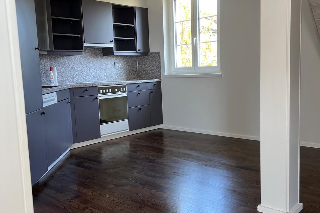 Pièce lumineuse sous les combles avec un parquet foncé soigné